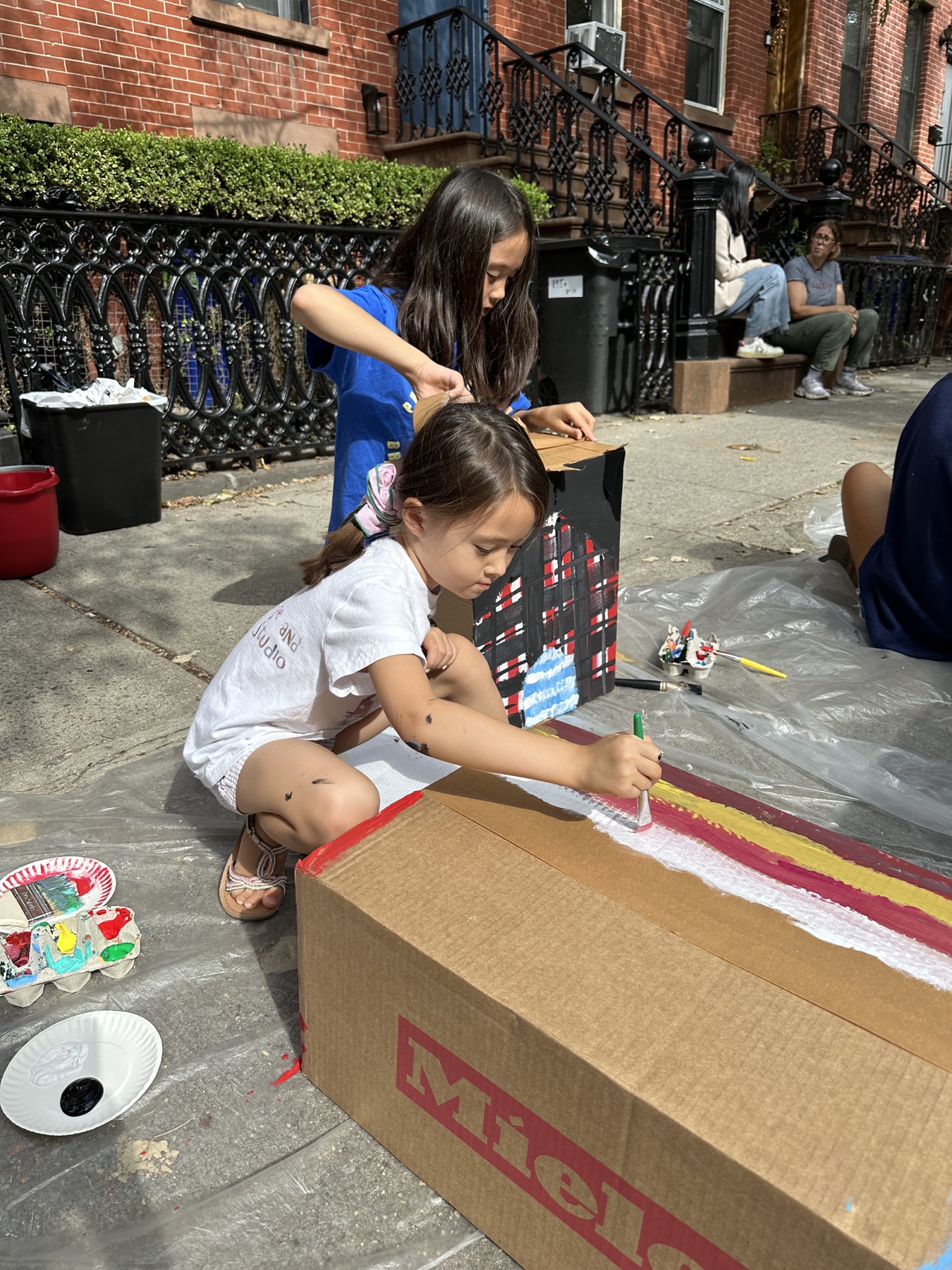 Children painting cardboard buildings on the 8th St sidewalk
